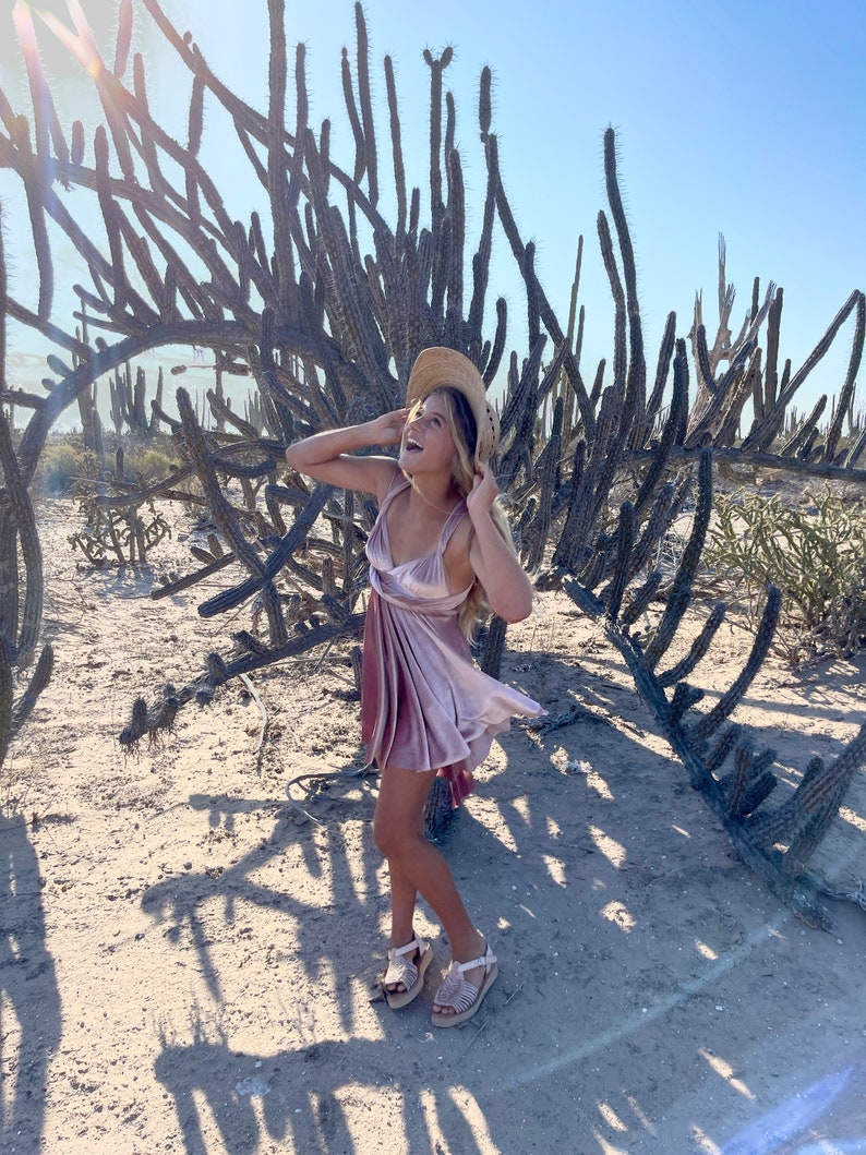 Girl in a pink velvet multiway dress and sun hat in a cactus landscape